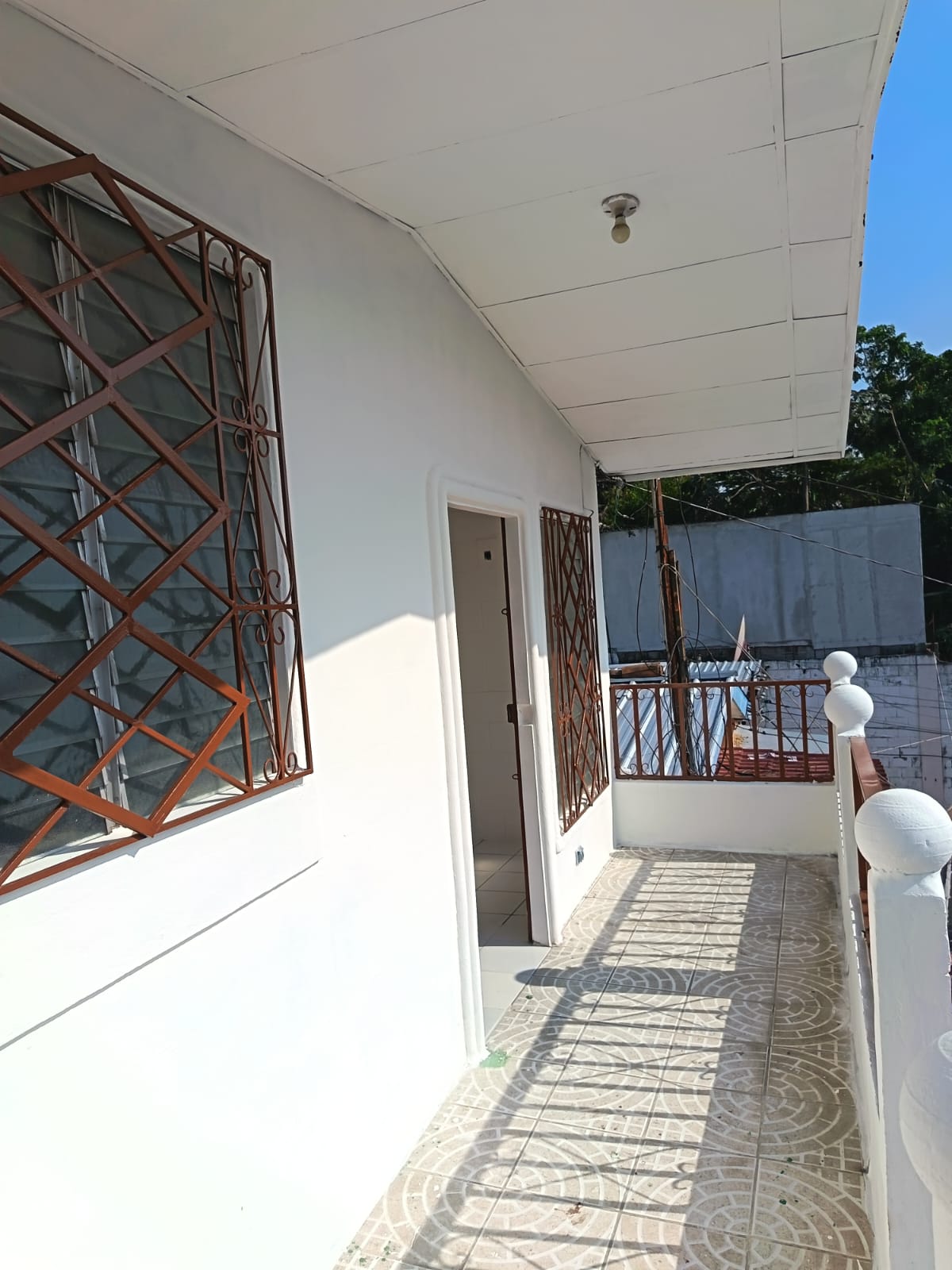 Entrada principal en segundo nivel con pasamano y ventanas con rejillas