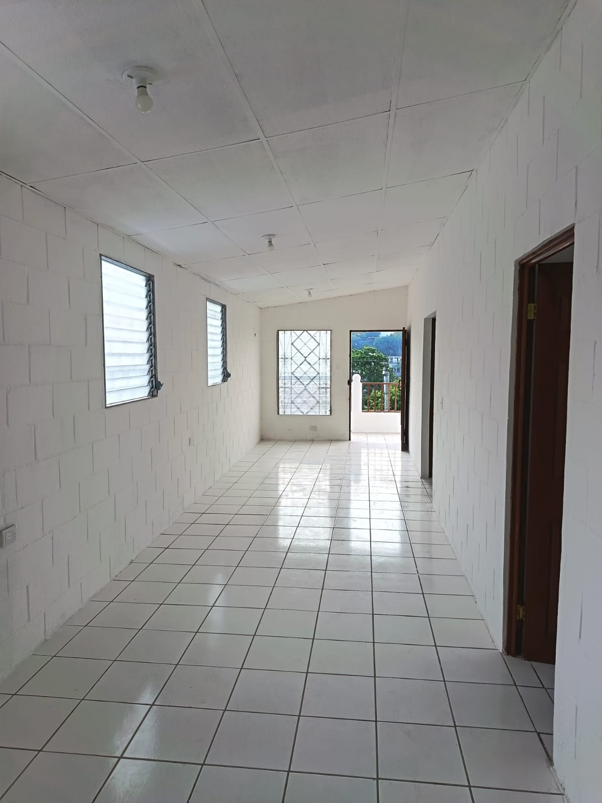 Vista de sala tipo pasillo con paredes blancas  piso ceramico blanco