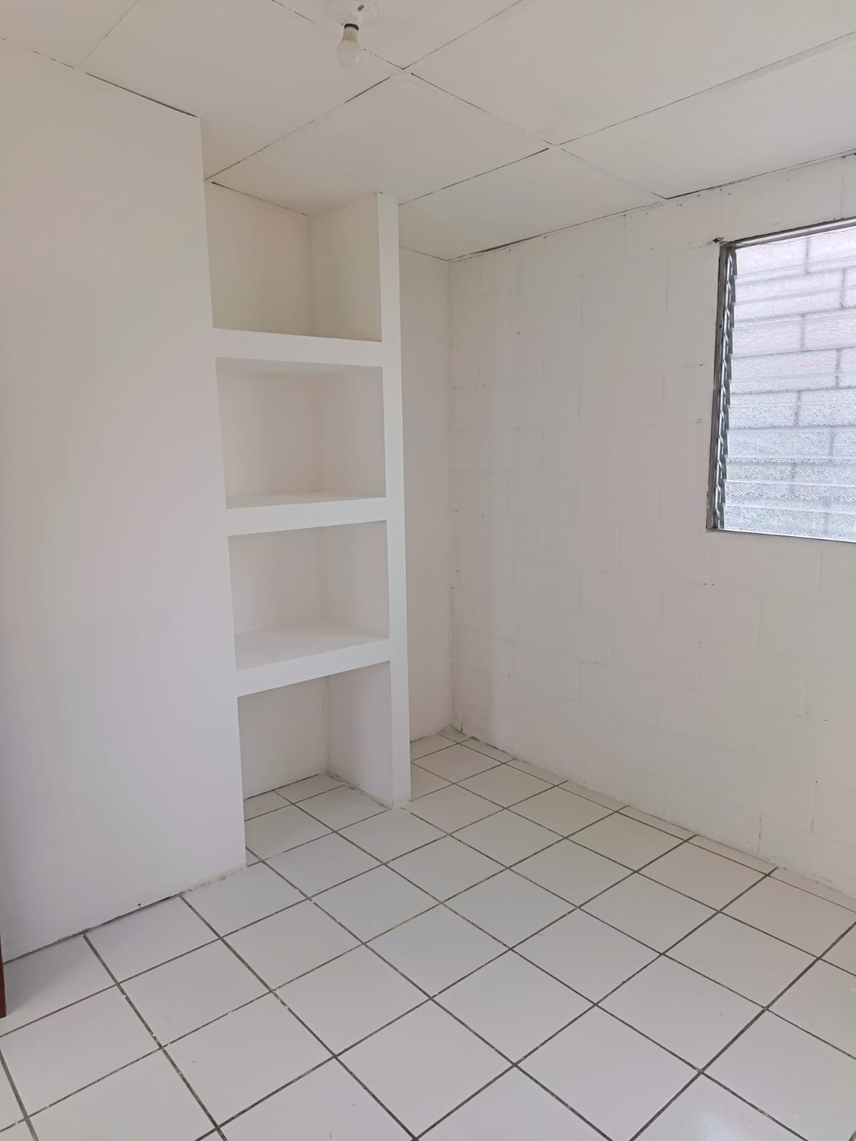 Habitación con con espacios para colocar ropa en diferentes niveles y ventana tradicional