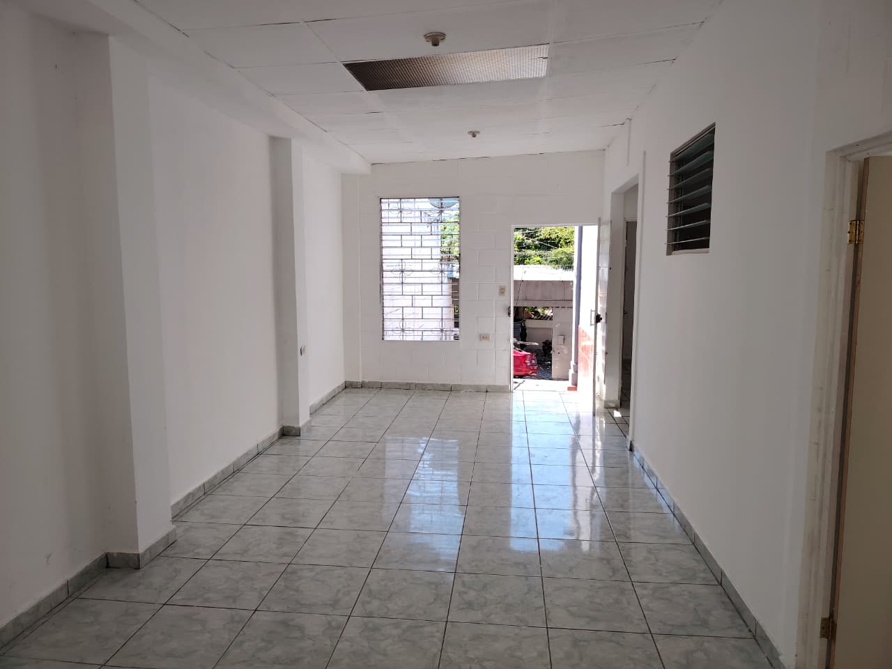 Sala principal con paredes blancas y ventana tradicional con vista hacia afuera