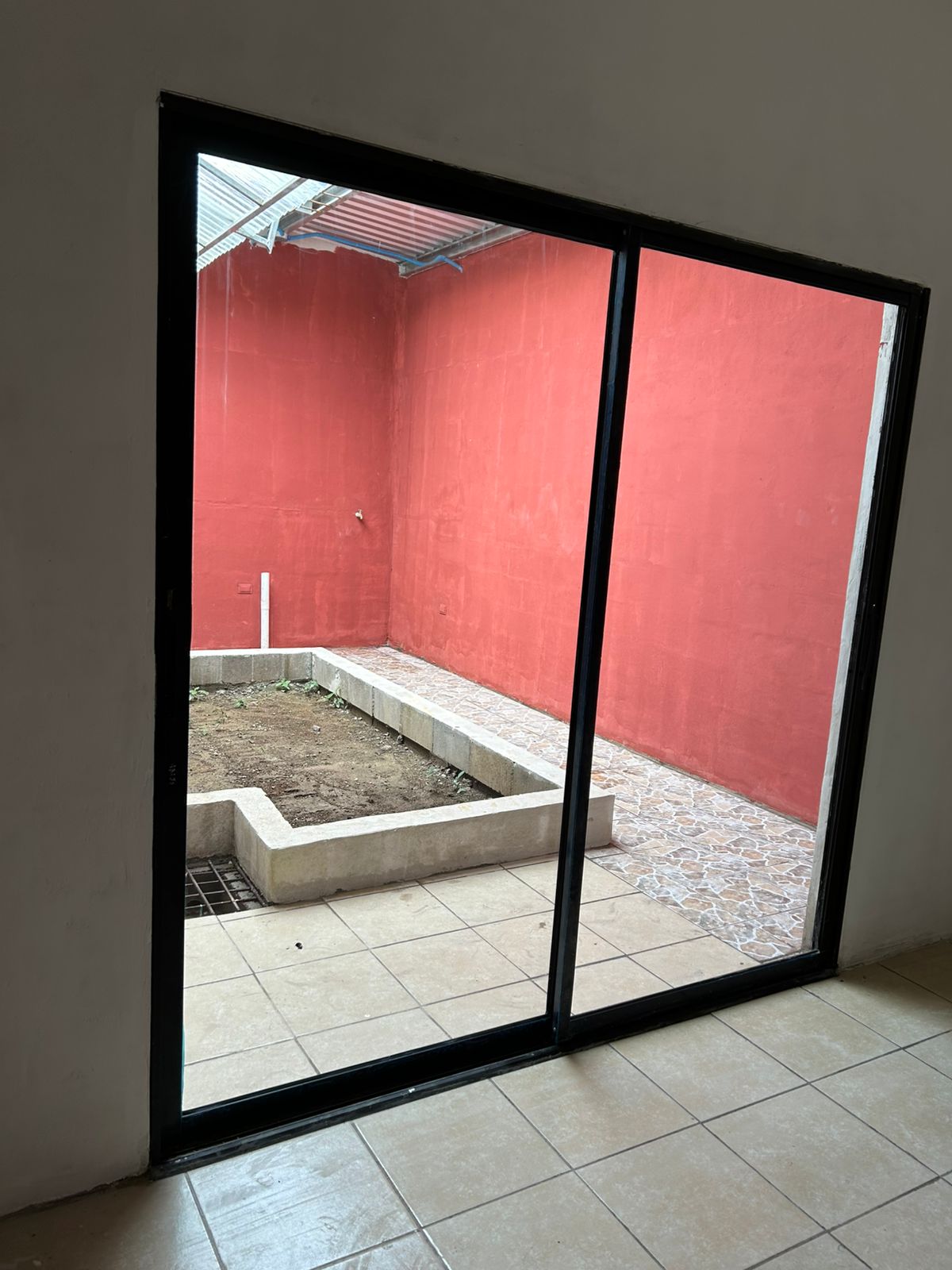 Puerta corediza y salida hacia patio con jardin, piso ceramico y antiderrapante
