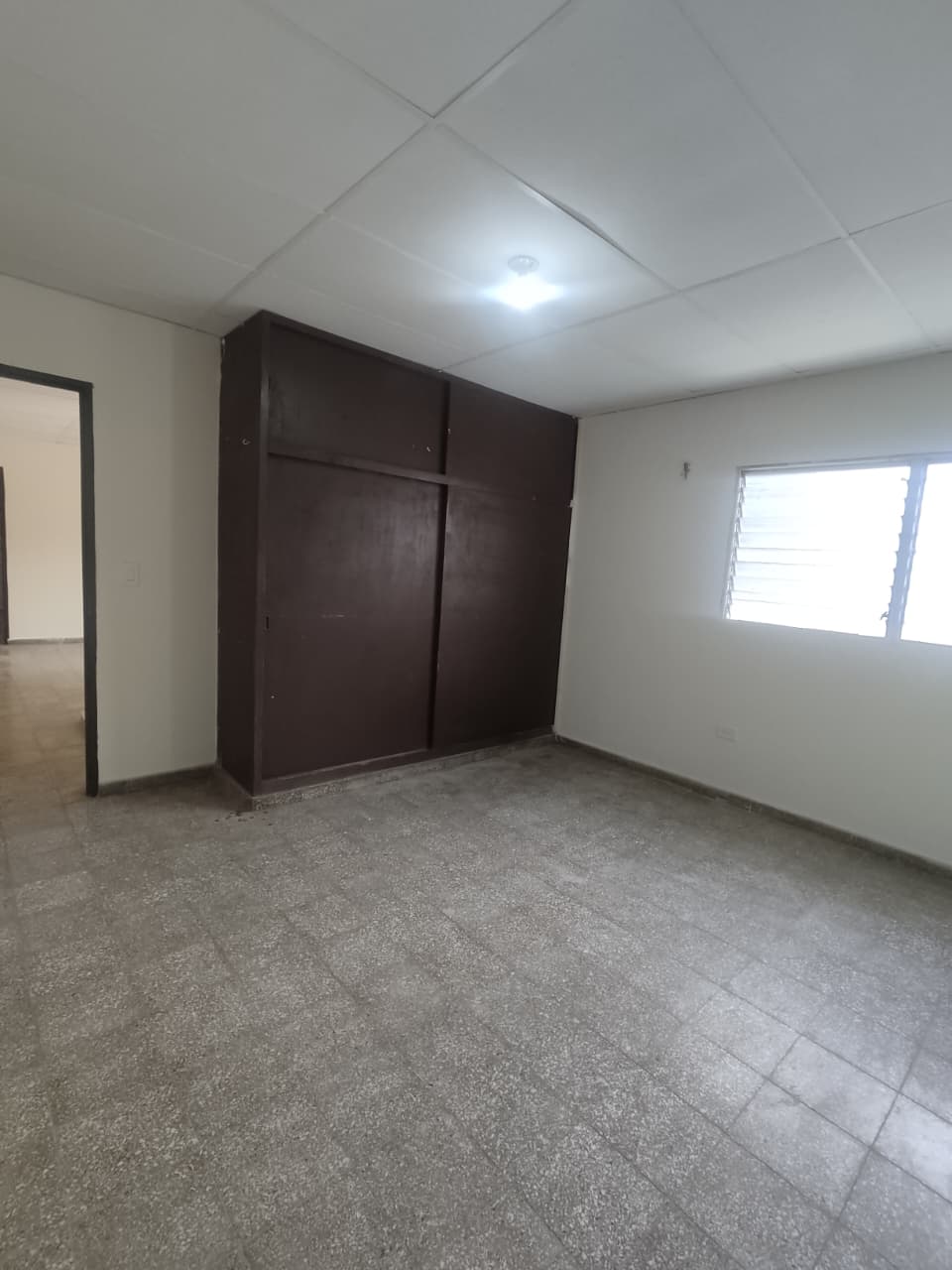 Habitación vacia con closet, ventana tradicional e iluminacon artificial