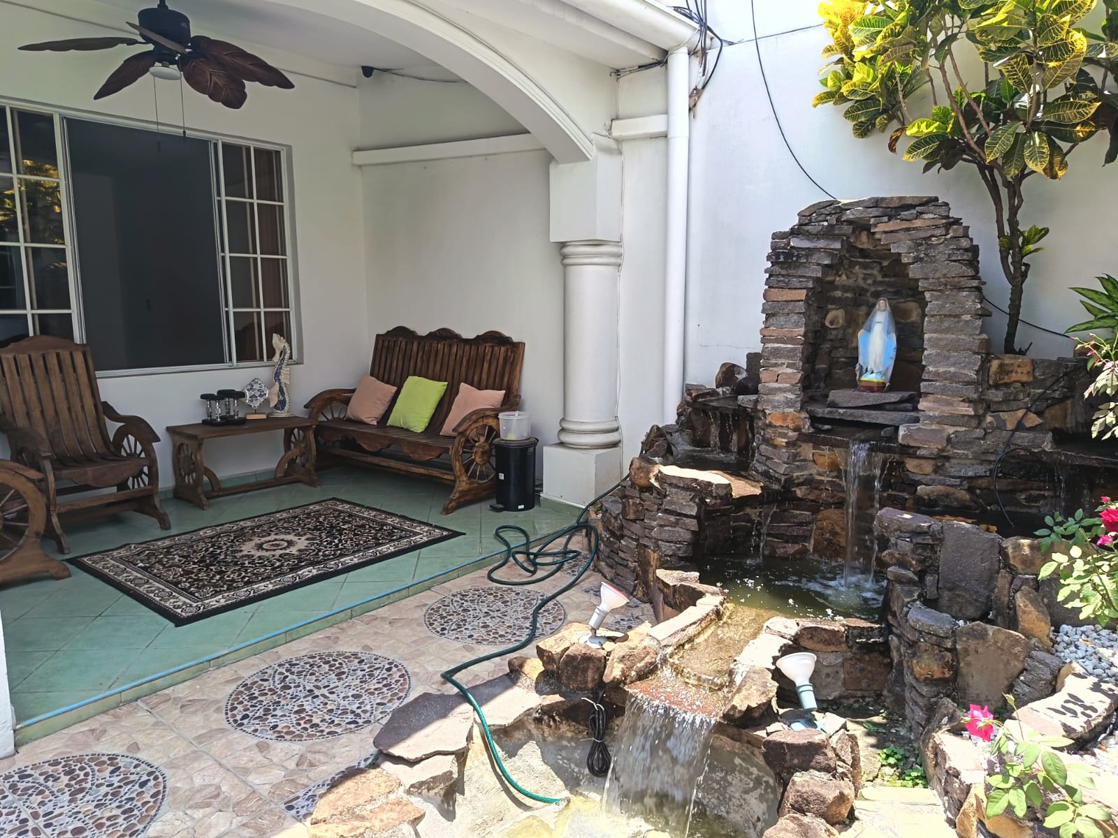 Sala de estar exterior junto a fuente con la imagen de una virgen