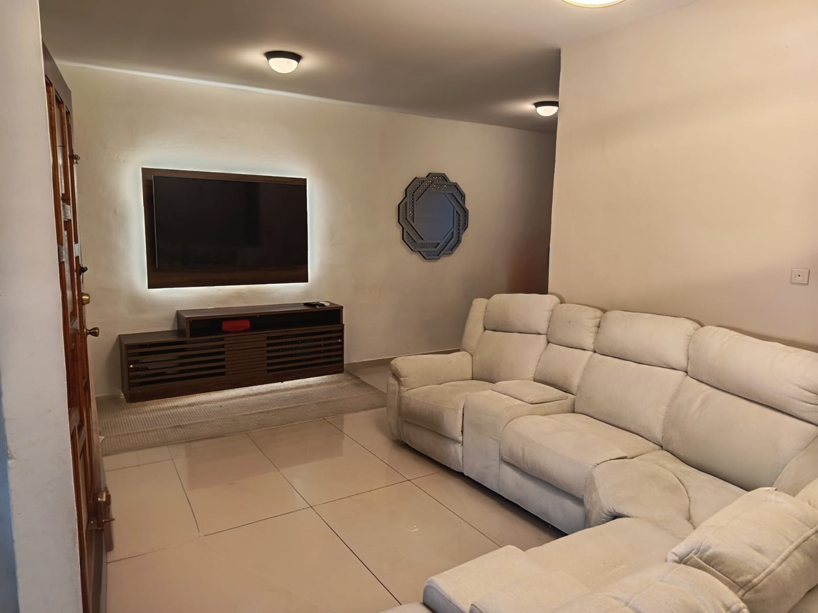 Sala con juego de sillones y tv en pared