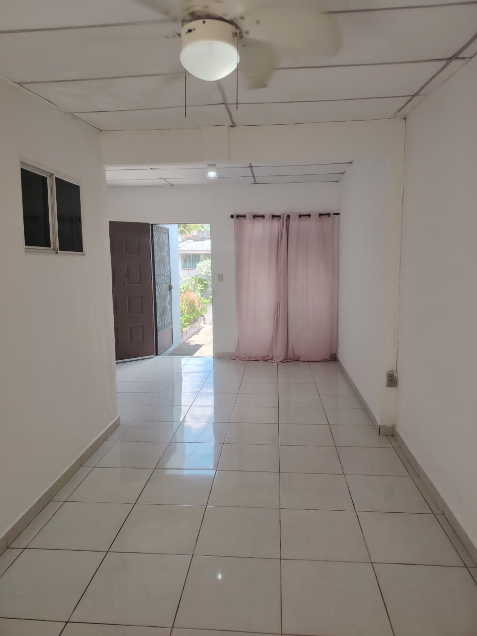 Entrada principal con ventana tradicinal y cortinas color rosa