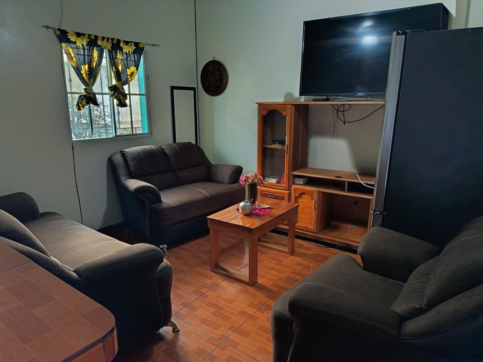 Sala principal con sillones oscuros y cortinas amarillas