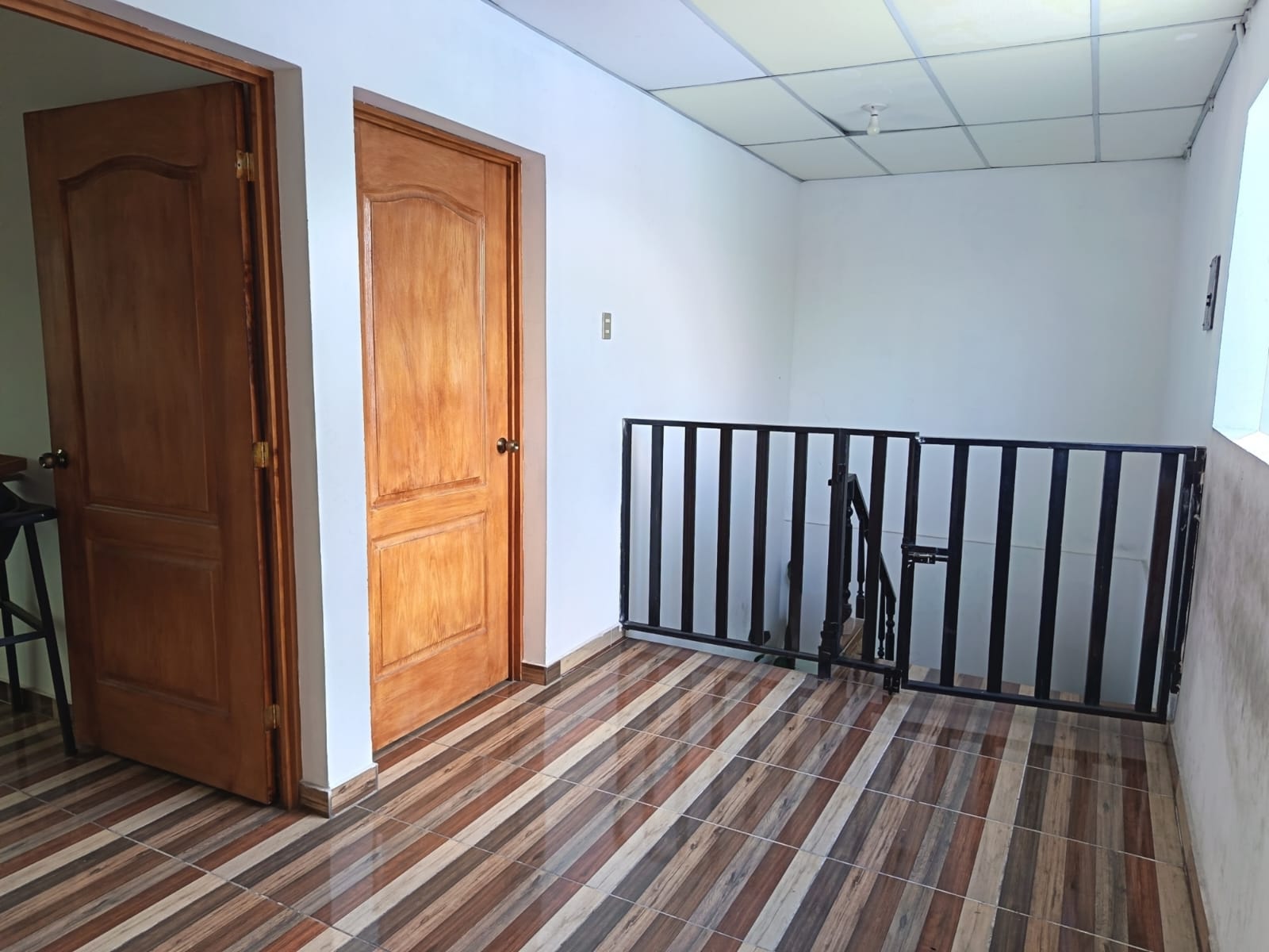 Pasillo con puertas de madera y barandal de metal negro